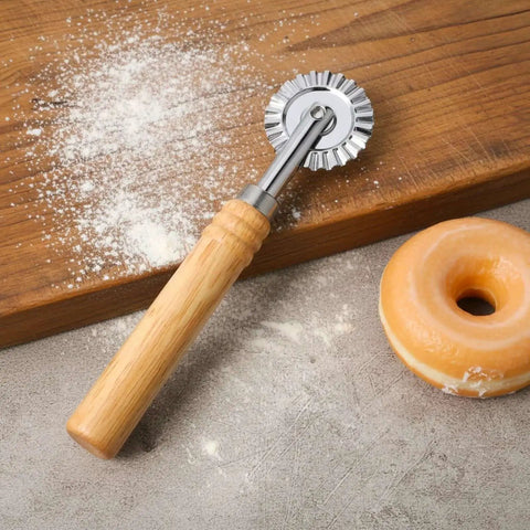 Versatile Long Handle Pastry And Pasta Cutter Wheel With Crinkle Edge For Effortless Slicing Of Ravioli Dumplings And Lasagna Pierogi And Beautiful Lattice Crusts Stainless Steel Construction TIESOME on a wooden board with doughnut nearby