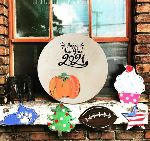Decorative crafts with Happy New Year 2021 sign, pumpkin, cupcake, and holiday-themed designs on window ledge