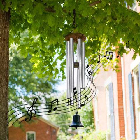 Wind chime with silver tubes hanging from a tree branch with musical notes overlay, outdoors near a brick house