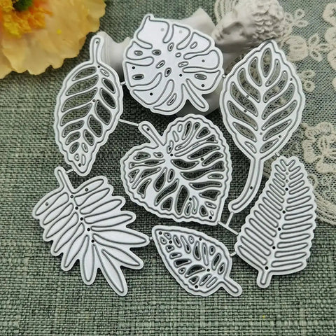 Totally Seven Piece Leaf Die Cut Set For Scrapbooking And Card Making; carbon steel dies in various plant leaf shapes on fabric background.