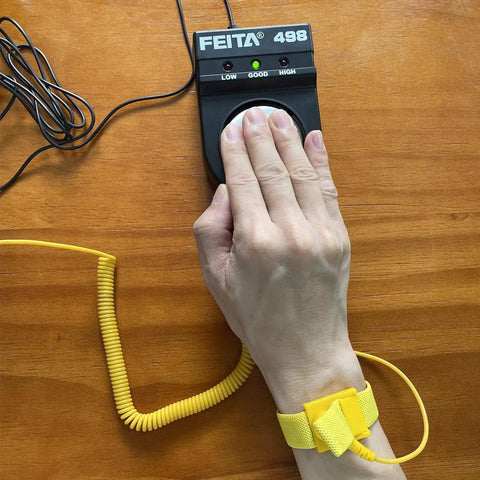 Person using Essential Anti Static ESD Wrist Strap Tester FEITA 498 with banana jack, showing grounded wristband in action