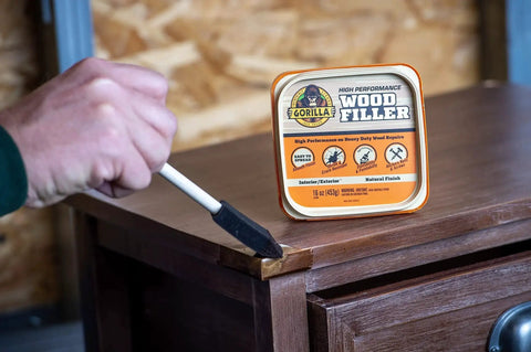 Person applying All Purpose Wood Filler Natural Finish 16 Oz Water Resistant Indoor Outdoor Use with brush on wooden furniture