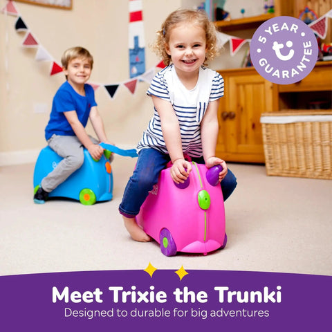 Children riding on pink and blue ride-on suitcases indoors, Ride On Kids Suitcase For Travel And Fun Tow Along Toddler Luggage With Wheels.