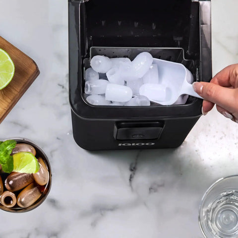 Compact Countertop Ice Maker 26 Lbs Per Day Fast Ice Includes Scoop And Basket with ice cubes being scooped on marble countertop.