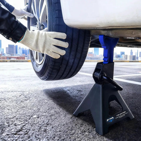 3 Ton Heavy Duty Car Jack Stands Set With Adjustable Height From 11.22 To 16.77 Inches For Lifting SUVs Small Trucks And Pickups Up To 6,000 Lb Each For Safe Automotive Maintenance lifting a vehicle, side view with gloved hands adjusting the tire.