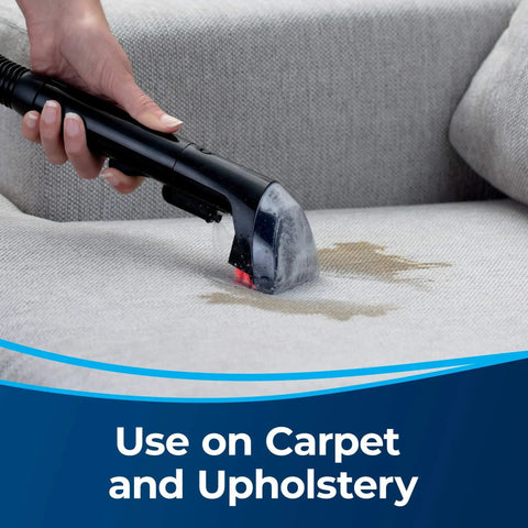 Close-up of a black Bissell 3-inch tough stain tool cleaning upholstery on a sofa