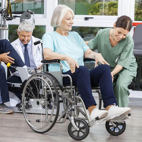Elderly woman in a wheelchair with a nurse assisting, doctor writing notes on the side, medical setting with large windows.