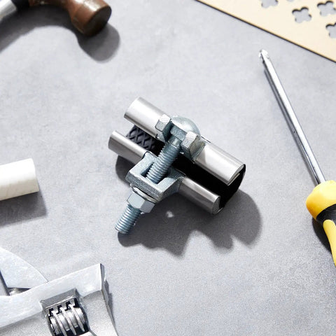 Two Pack Half Inch Pipe Repair Clamp With Single Bolt Stainless Steel Copper Pipe Repair Kit on gray surface with tools