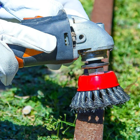 Close-up of a Three Pack 4 Inch Wire Wheel Brush For Angle Grinders With Five Eighths Inch Arbor Carbon Steel Wire 0.02 Inch in use outdoors.