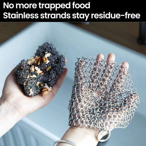 Hands holding cast iron scrubber with stainless steel chainmail next to a soiled sponge in a kitchen sink, showcasing its residue-free properties.