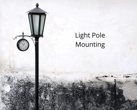 Black street lamp with clock on a concrete wall background displaying the text 'Light Pole Mounting'.