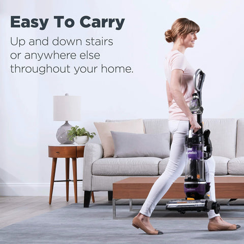 Eureka PowerSpeed NEU202 upright vacuum cleaner, purple, being carried by a person in a living room.