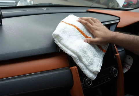 60 Pack 16 By 19 Inch Terry Bar Mop Rags For Cleaning Absorbent And Durable Cotton Cloths Multipurpose Shop Towels Reusable Rags For Home Office Garage Kitchen And More. White cotton rag with an orange stripe wiping a car dashboard.