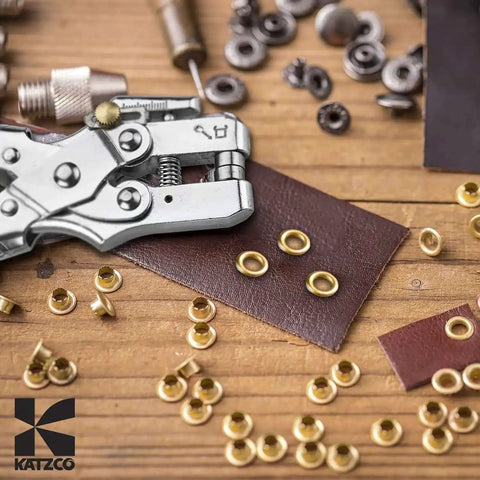 All In One Grab And Go Eyelet Grommet Pliers Kit With 1 Hole Punch and 100 Gold Grommets for leather crafting on wood surface.