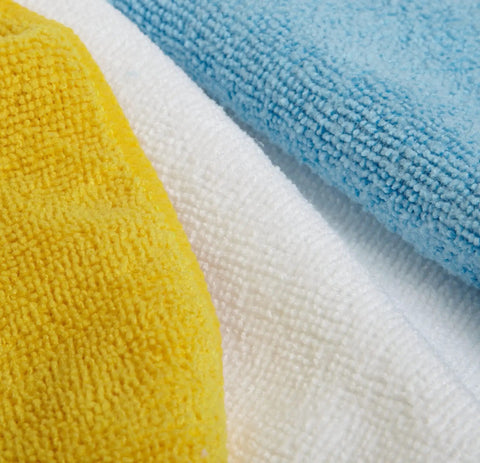 Close-up of ultra soft microfiber cleaning cloths in blue, white, and yellow, part of the pack of 24 for car detailing.