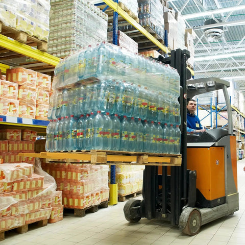 Forklift with 92 Inch Forklift Extensions For 4.5 Inch Wide Forks Heavy Duty Pair lifting a pallet of bottled water in a warehouse.