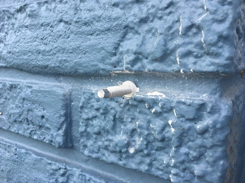 Installed PanelMate Pro Storm Panel Anchor 2-1/4 Inch in blue concrete wall, carbon steel with Stalgard coating visible.