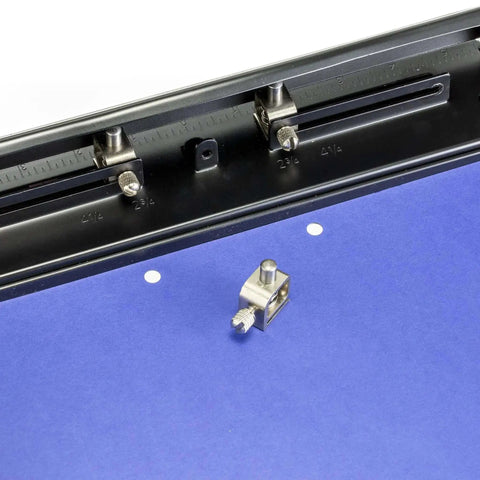 Close-up of adjustable three-hole punch for office documents with 11 sheet capacity, showing blue paper and black metal punch tool.