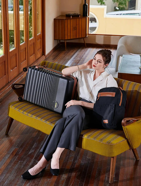 Woman sitting with Airline Approved Carry On Luggage 22x14x9, 20 Inch ABS Hard Shell Suitcase With TSA Lock beside her on a retro couch.
