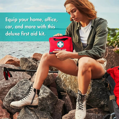 Bright Reflective 309 Piece First Aid Kit With Bandages Moleskin Pad And Emergency Blanket in hand by traveler on rocky shore