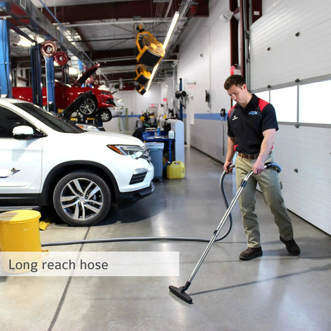Technician using Pro Wall Mount Garage And Car Vacuum With 50 Ft Hose And Tools on workshop floor