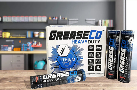 Greaseco Heavy Duty Lithium Complex grease tubes and box on a workbench in a garage setting.
