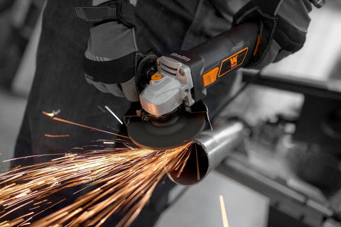 Powerful 7 Amp Angle Grinder With A Four And A Half Inch Wheel, 11,000 RPM, Lightweight Design With Rubber Grip, in use cutting metal.