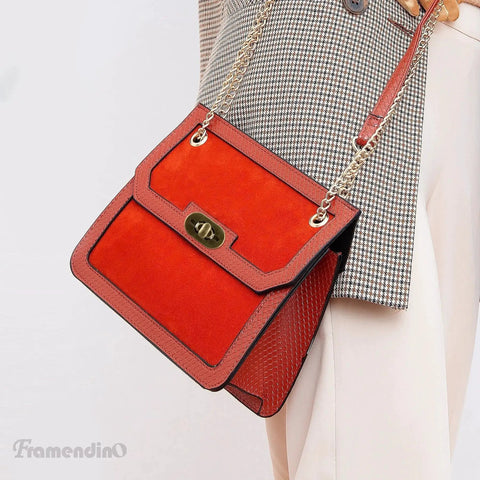 Red crossbody bag with twist lock clasp and chain strap, styled with a plaid blazer