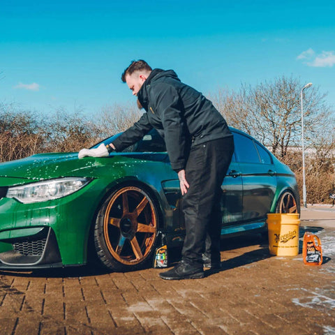Person using One Step Car Wash And Conditioner That Cleans And Conditions Without Stripping Wax And Foams Away Dirt And Road Grime While Preserving Wax Protection For A Dope Shine Meguiar's Gold Class 1.89L on green car.