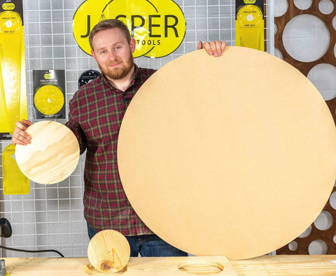 Man holding large and small wooden circles cut with Circle Cutting Router Jig With Pro Grade Precision For Making Perfect Circles From Two And A Quarter Inches To Eighteen And One Sixteenth Inches In One Sixteenth Inch Increments 256 Circle Sizes Industrial Grade Polycarbonate Lifetime Guarantee
