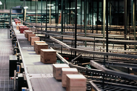 Conveyor system with cardboard boxes moving through a warehouse distribution area.