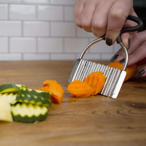 Crinkle Cutter For Fruits And Veggies With Non Slip Comfort Rubber Handle And Zigzag Stainless Steel Blade, slicing vegetables on a board.