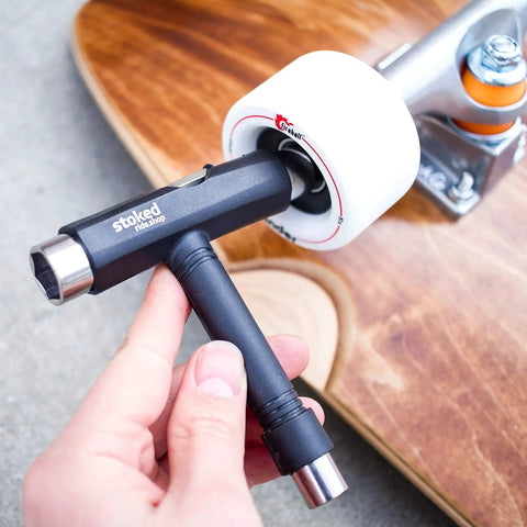 Person holding a skateboard tool next to a skateboard wheel with Reds Bearings 8 Pack for skateboards longboards scooters and spinners