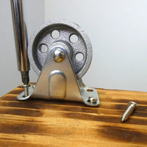 Installed 2-Inch Cast Iron Rigid Plate Caster With 1-1/4-Inch Wide And 2-Inch Diameter Silver Wheel on wooden surface