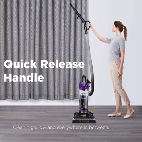 Eureka PowerSpeed bagless upright vacuum cleaner, purple, with quick-release handle; person using it.