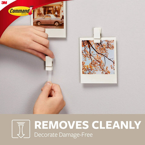 Hand hanging photo with Quartz Plastic Spring Clips 8 Pack For Dorm Décor Damage Free Hanging, easy removal shown on wall