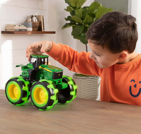 Child playing with John Deere Monster Treads Lightning Wheels Monster Truck Toy with motion activated lights and oversized wheels.