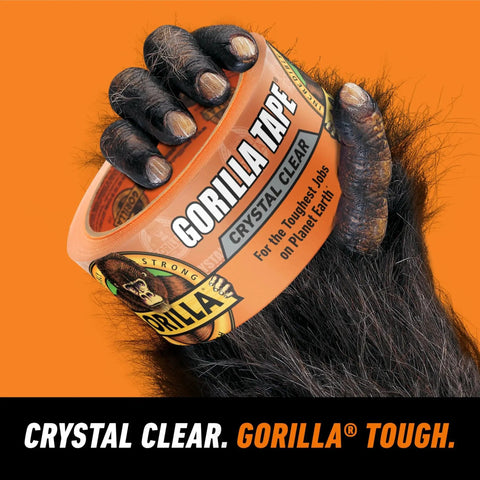 Gorilla hand holding Crystal Clear Tape 1.88 Inch By 18 Yard Weather Resistant Indoor Outdoor in orange packaging