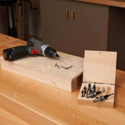 Six-Piece Carbide-Tipped Countersink Set With Brad Point Pilots In Wooden Case with screws and drill on workspace