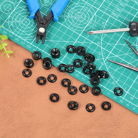 Top-down view of #8 black finish stainless steel cup washers, countersunk, 200 pcs, scattered with pliers on a cutting mat
