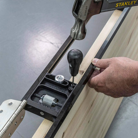 Close-up of All-In-One Adjustable Door Hinge Jig Installation Kit For 2 Ft 6 In To 9 Ft Doors being used on a wooden door.