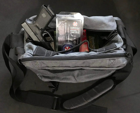 Open tactical bag displaying a handgun, Mil Spec Gun Grease, and ammunition inside compartments, shot from above