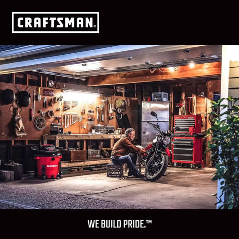 Man working on motorcycle in a well-organized garage with tools displayed on the wall and Craftsman tool cabinets.