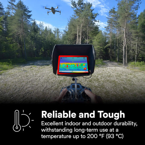 Person operating a drone with thermal imaging monitor in a forest clearing, showing temperature durability up to 200°F (93°C).