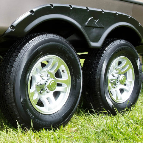 Dual trailer wheels with silver rims and black tires under a green fender