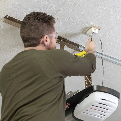 Man installing Heavy Duty Garage Door Opener Surge Protector For Single Opener With 15A 125VAC 1875W UL Listed Protection to outlet