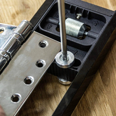 All-In-One Adjustable Door Hinge Jig Installation Kit For 2 Ft 6 In To 9 Ft Doors, No-Fuss Hands-Free Foot Operated Lifter, Sturdy Door Stand, And Pro Router Bit By Trend showing close-up of hinge placement on wooden surface.