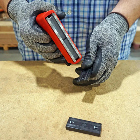 Person holding 100 Pound Pull Magnetic Lifter With Ergonomic Handle Red above a wooden surface