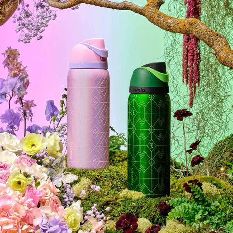 Pink and green FreeSip Insulated Stainless Steel Water Bottles with straws, set in a floral garden background