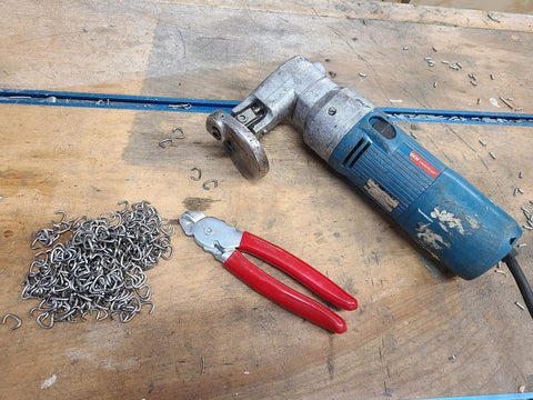 Heavy Duty Hog Ring Pliers With 3/8 Stainless Hog Rings Spring Loaded Jaws PVC Grips 7 Inch Auto Upholstery Tool next to rings on a workbench